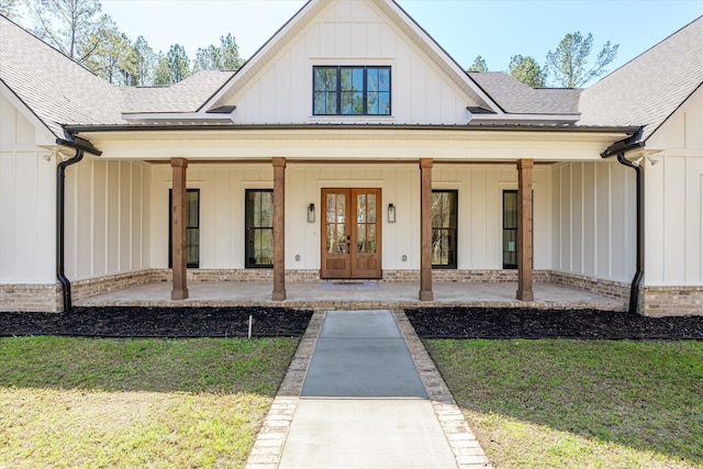 property entrance with a lawn, french doors, board and batten siding, and a shingled roof