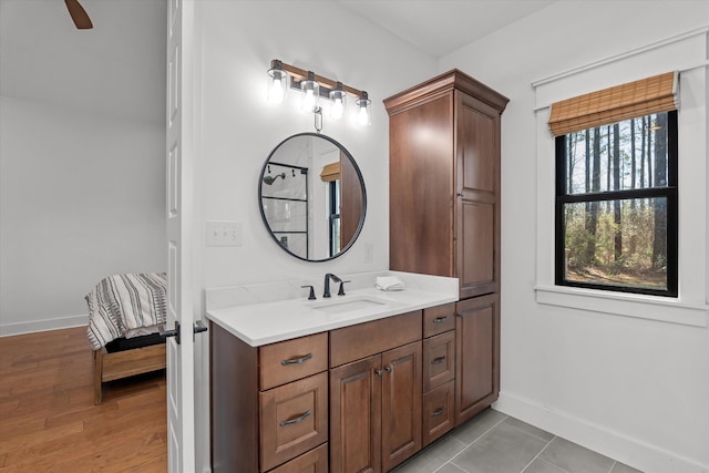 bathroom featuring vanity, ensuite bath, wood finished floors, and baseboards