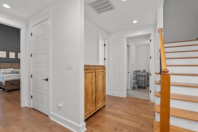 hallway with visible vents, light wood-style flooring, recessed lighting, baseboards, and stairs