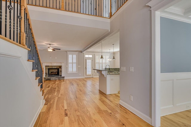 824 Brasstown Ct, Evans, GA 30809 - unfurnished living room with ceiling fan, light wood finished floors, crown molding, a stone fireplace, and stairway