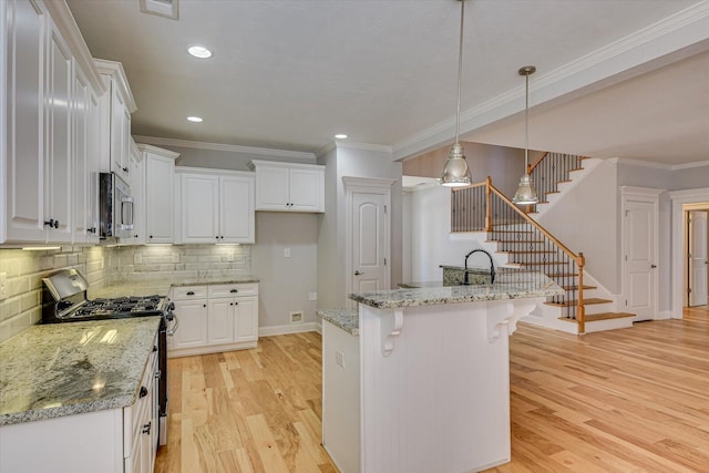 824 Brasstown Ct, Evans, GA 30809 - kitchen featuring appliances with stainless steel finishes, crown molding, white cabinets, light wood-type flooring, and backsplash