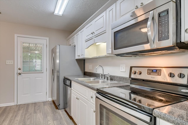 kitchen featuring light wood-type flooring, a sink, white cabinets, and stainless steel appliances