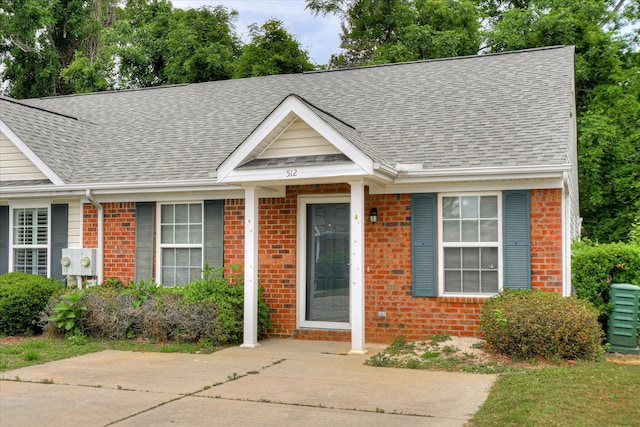 view of front of home with brick siding and roof with shingles