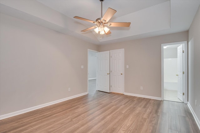 unfurnished bedroom with light wood-style floors, baseboards, ensuite bathroom, and a ceiling fan