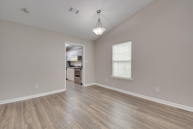 unfurnished room featuring visible vents, baseboards, light wood finished floors, and lofted ceiling