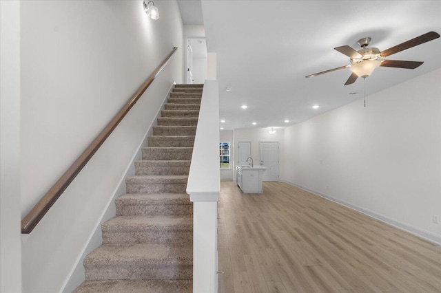 stairway featuring hardwood / wood-style floors, ceiling fan, and sink