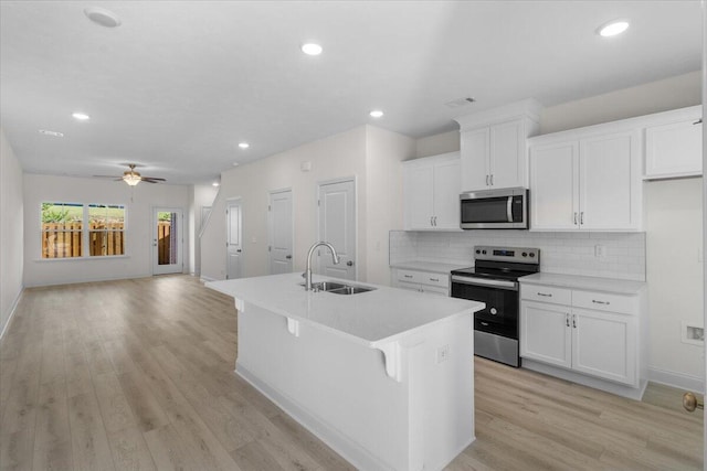 kitchen featuring ceiling fan, sink, an island with sink, white cabinets, and appliances with stainless steel finishes