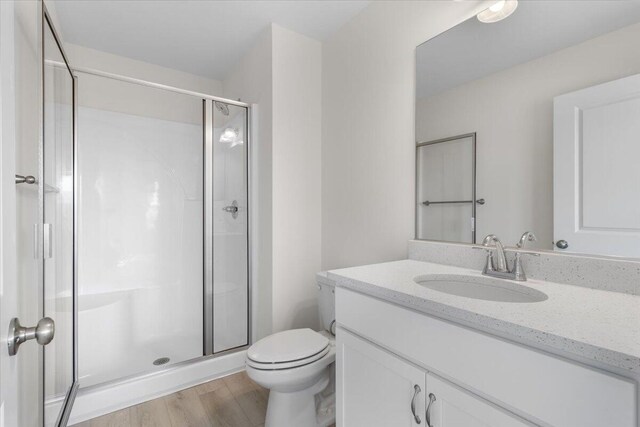 bathroom with vanity, hardwood / wood-style flooring, toilet, and an enclosed shower