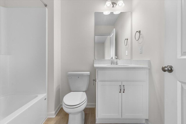 full bathroom featuring bathtub / shower combination, vanity, hardwood / wood-style flooring, and toilet