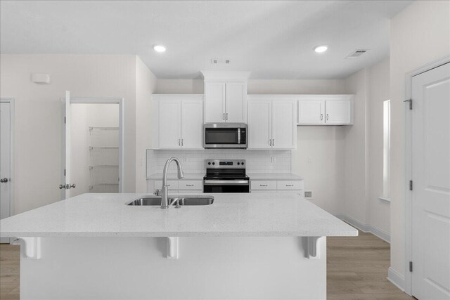 kitchen featuring a kitchen breakfast bar, sink, stainless steel appliances, and an island with sink