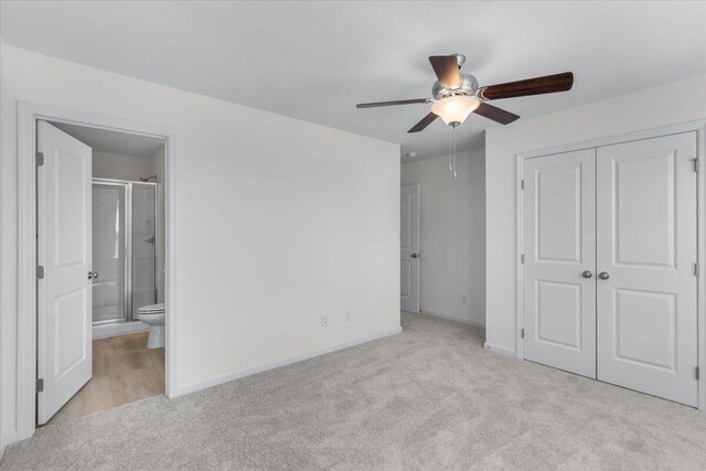 unfurnished bedroom featuring light carpet, connected bathroom, a closet, and ceiling fan