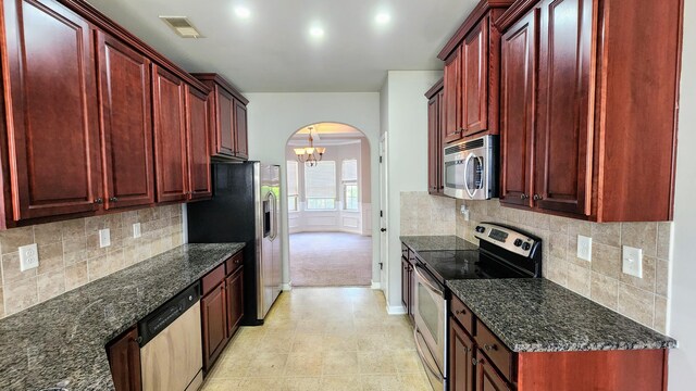 2806 Huntcliffe Dr, Augusta, GA 30909 - kitchen with stainless steel appliances, dark brown cabinets, arched walkways, and dark stone countertops