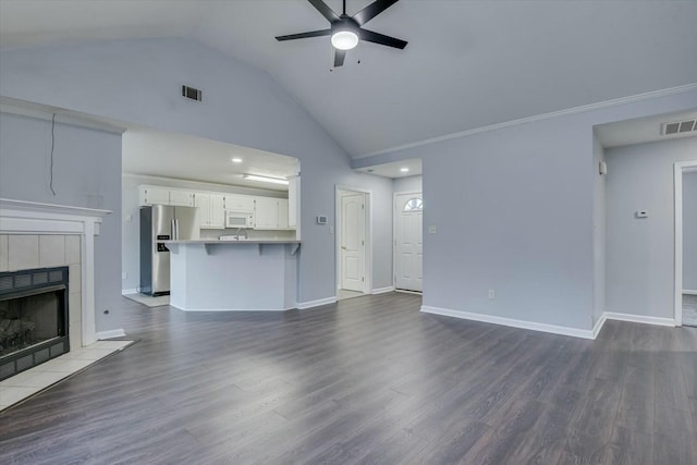 unfurnished living room featuring dark wood-style flooring, visible vents, and a tiled fireplace