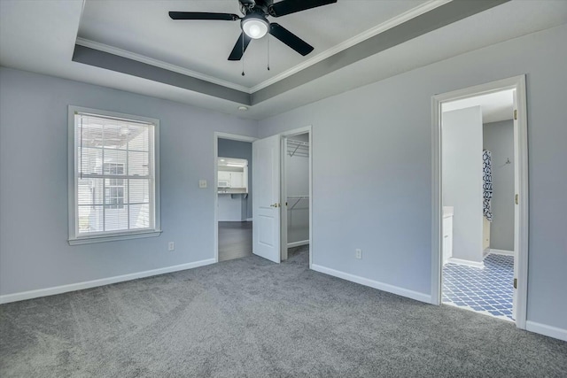 unfurnished bedroom with a tray ceiling, carpet flooring, crown molding, and baseboards