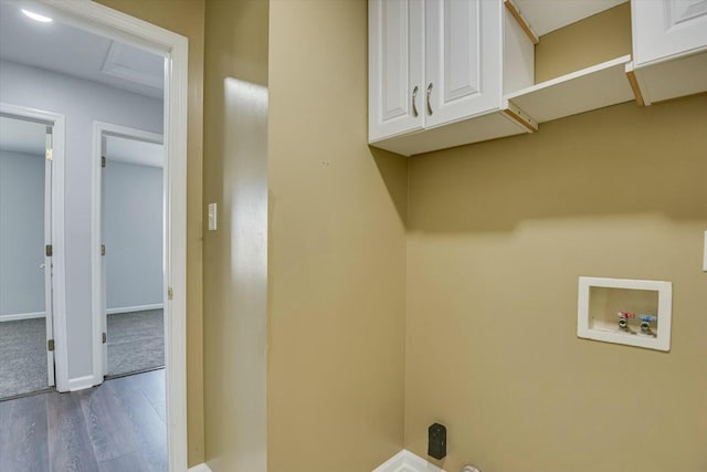 clothes washing area featuring washer hookup, cabinet space, baseboards, and wood finished floors