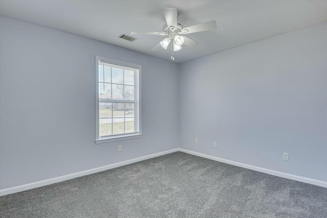 spare room with a ceiling fan, dark colored carpet, visible vents, and baseboards