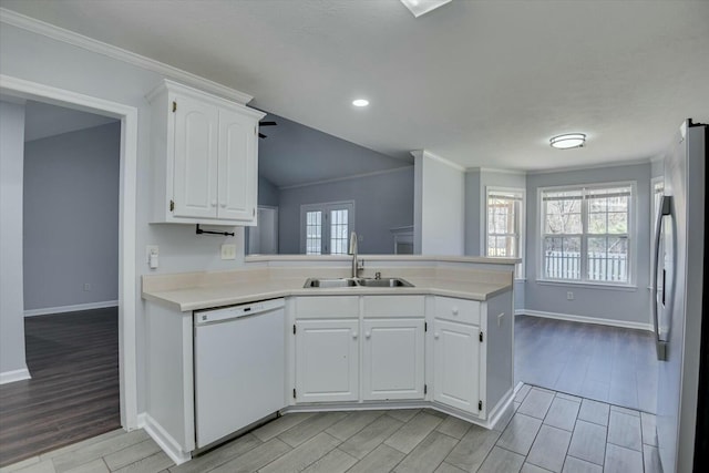 kitchen with a peninsula, wood finish floors, a sink, freestanding refrigerator, and dishwasher