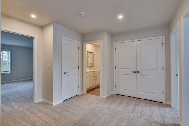 unfurnished bedroom with recessed lighting, light carpet, a sink, and baseboards