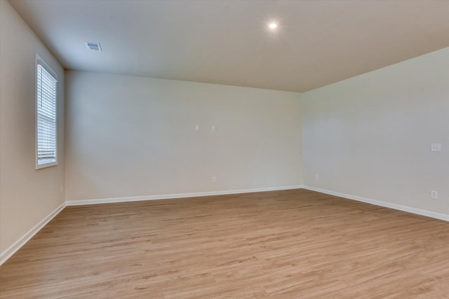 empty room featuring light wood-style floors, visible vents, and baseboards