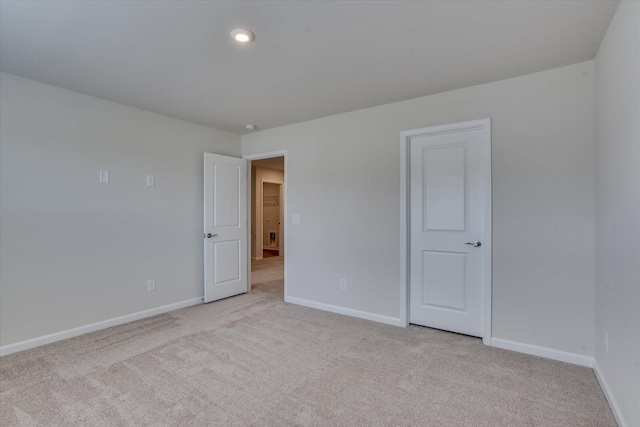 empty room featuring baseboards and light colored carpet