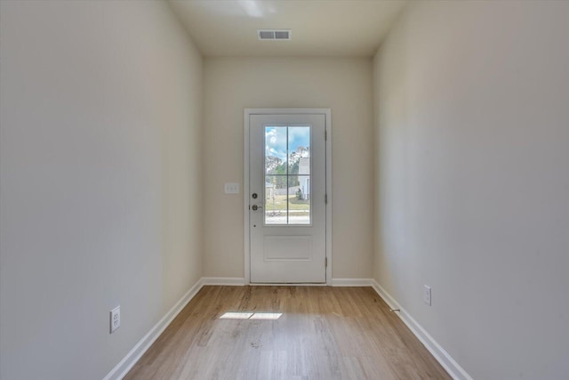 doorway with light wood-type flooring, visible vents, and baseboards