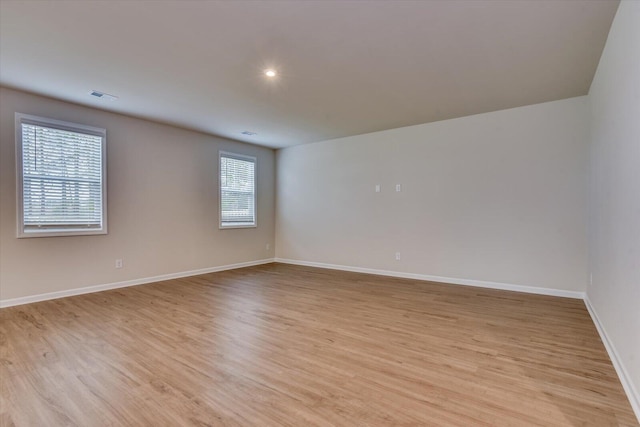 unfurnished room featuring light wood-type flooring, visible vents, baseboards, and recessed lighting