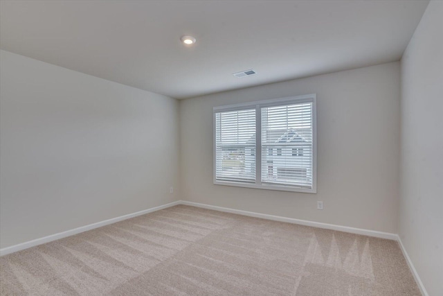 spare room featuring light carpet, visible vents, and baseboards