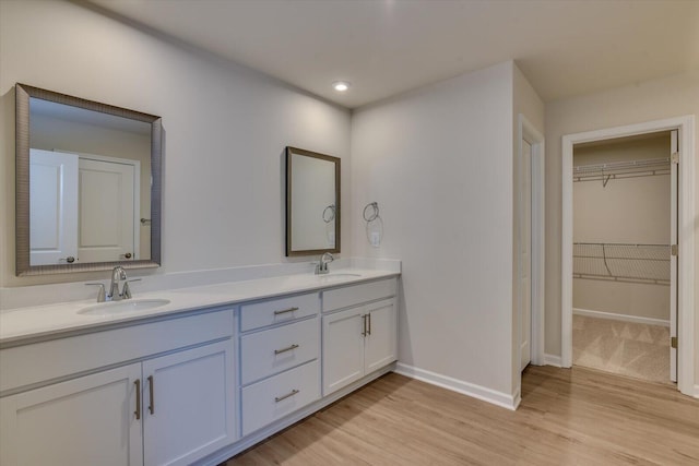 full bathroom with double vanity, baseboards, a sink, and wood finished floors