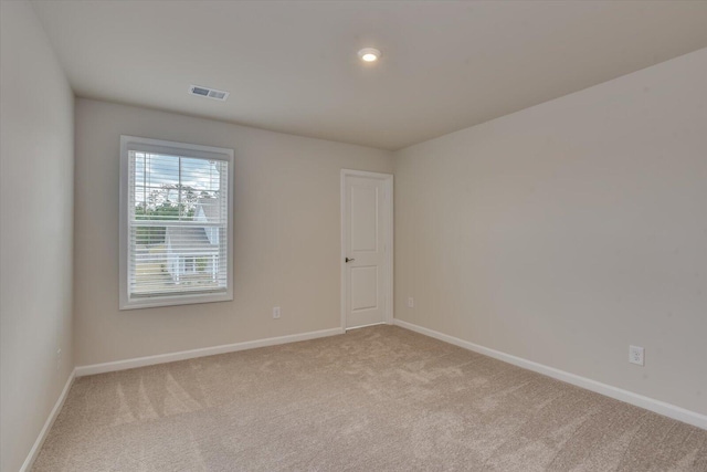 carpeted spare room featuring baseboards and visible vents