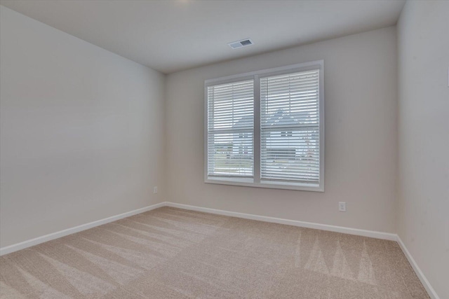 unfurnished room featuring baseboards, visible vents, and light colored carpet