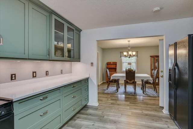 kitchen featuring decorative backsplash, green cabinetry, a notable chandelier, and black appliances