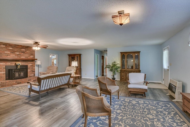 living room featuring dark hardwood / wood-style flooring, a textured ceiling, heating unit, and a wood stove