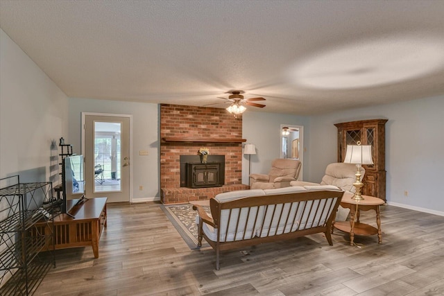 interior space featuring hardwood / wood-style floors, ceiling fan, a wood stove, and a textured ceiling