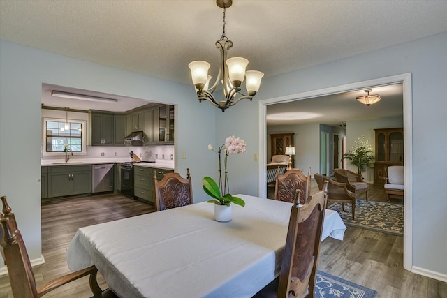 dining room featuring a chandelier, sink, dark wood-type flooring, and a textured ceiling