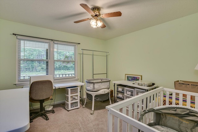 bedroom featuring a crib, light carpet, a textured ceiling, and ceiling fan