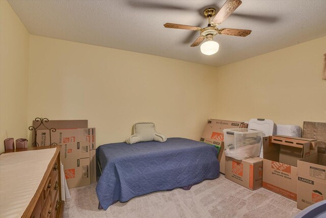 bedroom with a textured ceiling, ceiling fan, and light carpet