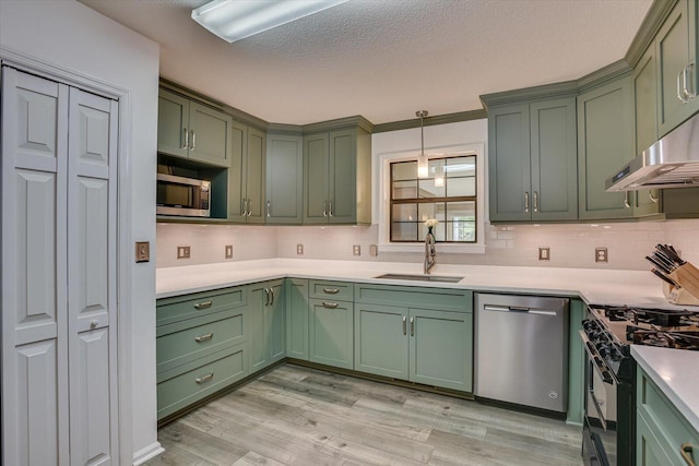 kitchen featuring appliances with stainless steel finishes, light wood-type flooring, green cabinets, and sink