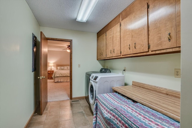 laundry room featuring ceiling fan, cabinets, independent washer and dryer, light colored carpet, and a textured ceiling