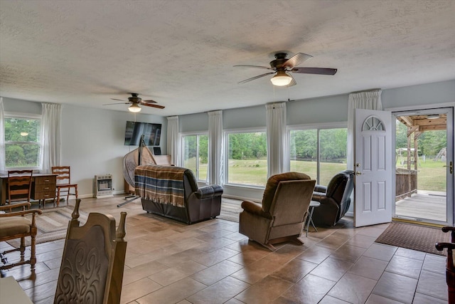 tiled living room featuring a textured ceiling, heating unit, and ceiling fan