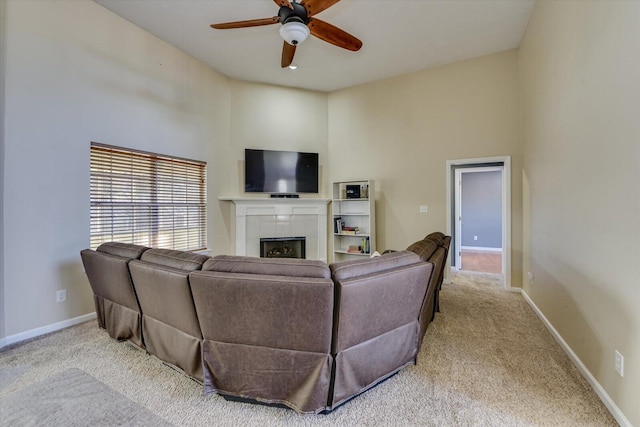 living room featuring a high ceiling, ceiling fan, light colored carpet, and a fireplace