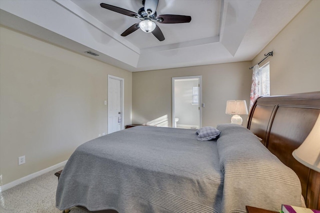 carpeted bedroom featuring a tray ceiling and ceiling fan