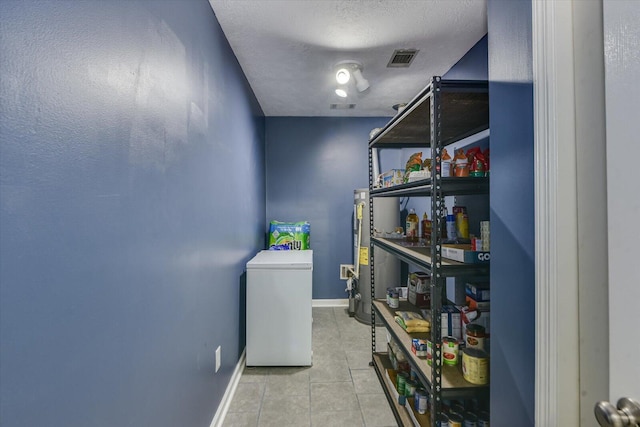 laundry room with light tile patterned floors and a textured ceiling