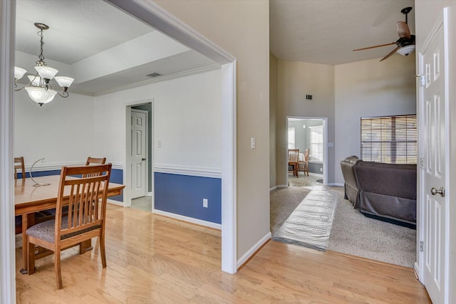 dining room with ceiling fan with notable chandelier and light hardwood / wood-style floors