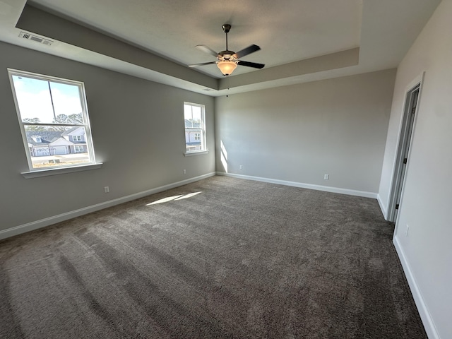 carpeted empty room featuring a raised ceiling and ceiling fan