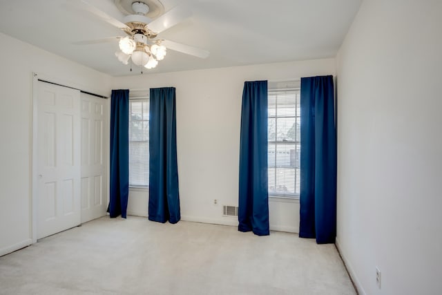 unfurnished bedroom with multiple windows, light carpet, a closet, and ceiling fan