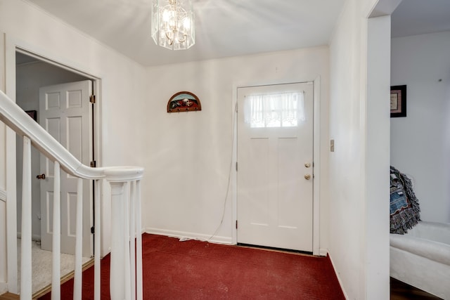 foyer featuring dark carpet and an inviting chandelier