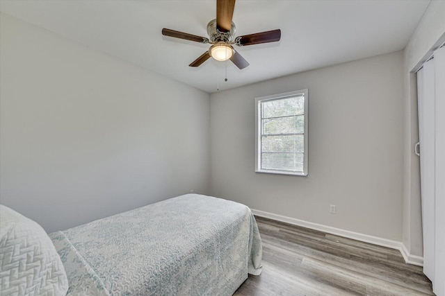 bedroom with a closet, a ceiling fan, baseboards, and wood finished floors