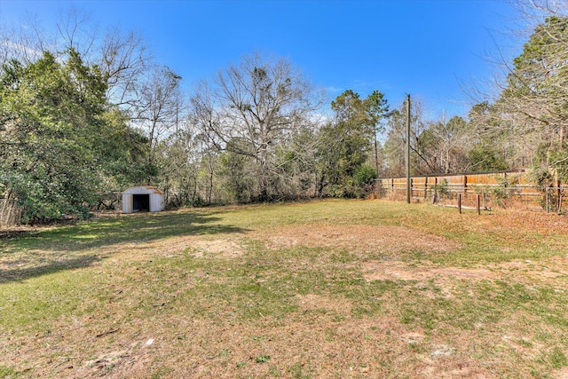 view of yard featuring a storage shed, fence, and an outbuilding