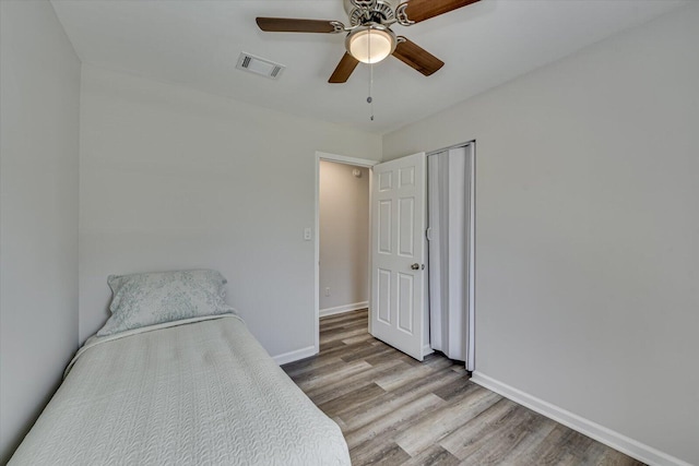 bedroom featuring light wood-type flooring, visible vents, baseboards, and ceiling fan