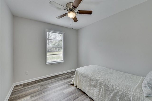 bedroom with a ceiling fan, wood finished floors, and baseboards